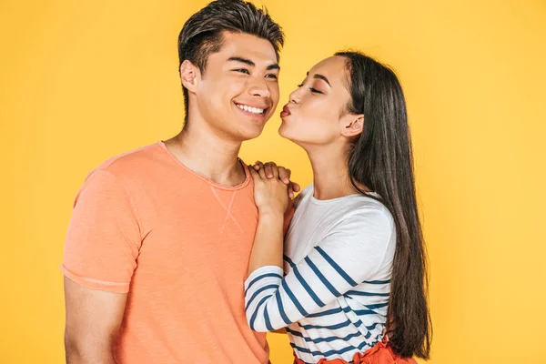 Bella asiatico ragazza baci felice fidanzato isolato su giallo — Foto stock
