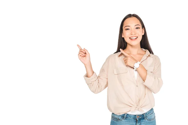 Cheerful asian woman pointing with fingers while looking at camera isolated on white — Stock Photo