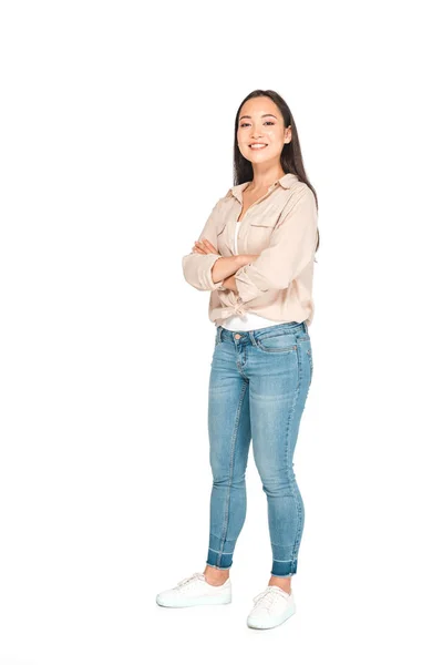 Atractiva mujer asiática posando en cámara con brazos cruzados sobre fondo blanco - foto de stock