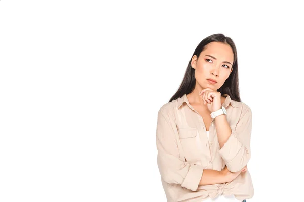 Femme asiatique réfléchie tenant la main près du visage et regardant loin isolé sur blanc — Photo de stock