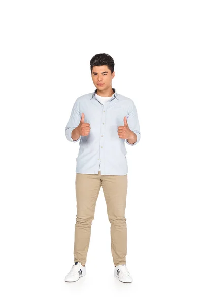Junge asiatische Mann zeigt Daumen nach oben, während Blick auf Kamera auf weißem Hintergrund — Stockfoto
