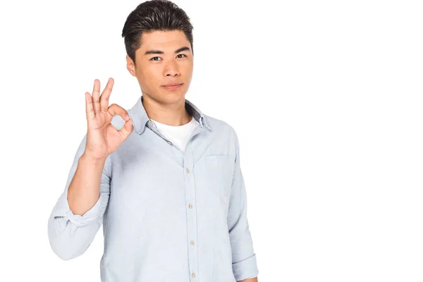 Joven asiático hombre mostrando ok signo mientras mira la cámara aislado en blanco - foto de stock