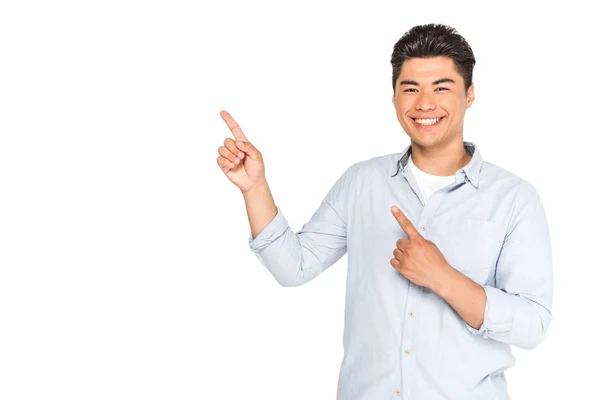 Joven asiático hombre apuntando con los dedos mientras sonriendo a cámara aislado en blanco - foto de stock