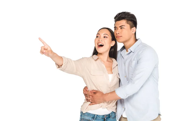 Handsome asian man hugging girlfriend pointing with finger isolated on white — Stock Photo