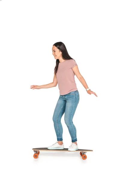 Cheerful asian girl riding longboard and smiling on white background — Stock Photo