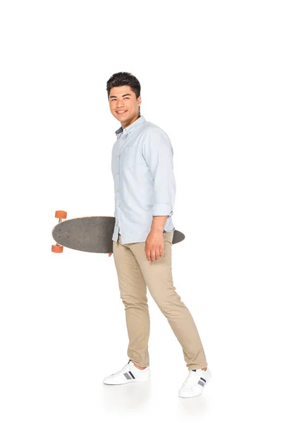 Beau asiatique homme tenant longboard tout en regardant caméra sur fond blanc — Photo de stock