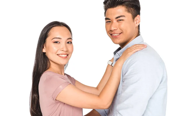 Happy asian woman holding hands on shoulders of smiling boyfriend while looking at camera isolated on white — Stock Photo