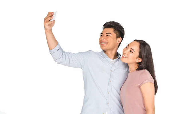 Cheerful asian couple taking selfie on smartphone isolated on white — Stock Photo