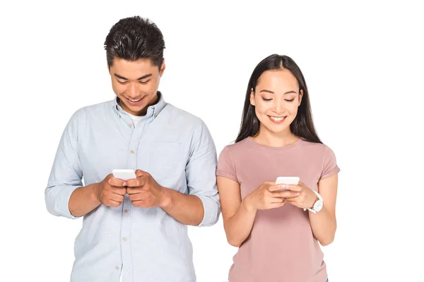 Jovem asiático casal sorrindo ao usar smartphones isolados no branco — Fotografia de Stock