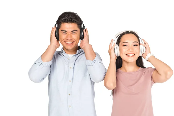 Щасливий азіатський чоловік і жінка дивиться на камеру, слухаючи музику в навушниках ізольовані на білому — стокове фото