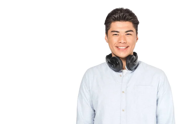 Guapo asiático hombre con auriculares en el cuello sonriendo a cámara aislada en blanco - foto de stock