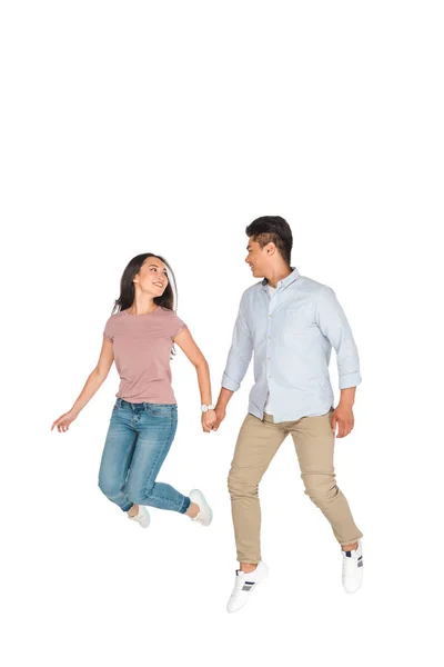Feliz asiático hombre y mujer saltar mientras cogido de la mano en blanco fondo - foto de stock