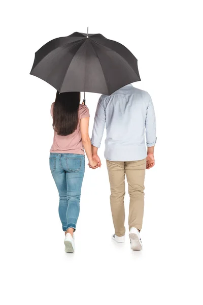 Back view of asian couple walking under umbrella and holding hands on white background — Stock Photo