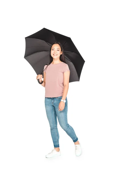 Alegre asiático menina segurando preto guarda-chuva e sorrindo para a câmera no branco fundo — Fotografia de Stock