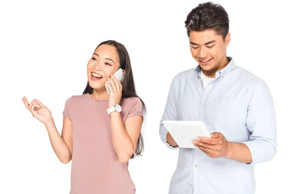 Fröhliche asiatische Frau spricht auf Smartphone in der Nähe Freund mit Laptop isoliert auf weiß — Stockfoto