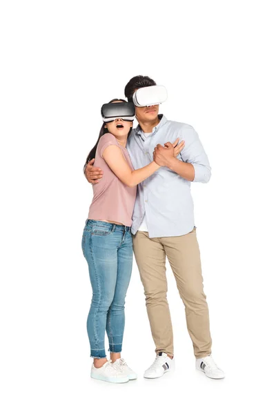 Verängstigtes Paar umarmt sich bei der Verwendung von Virtual-Reality-Headsets auf weißem Hintergrund — Stockfoto