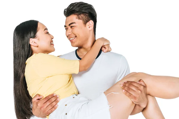 Щасливий азіатський чоловік тримає молоду дівчину на руках ізольовано на білому — стокове фото