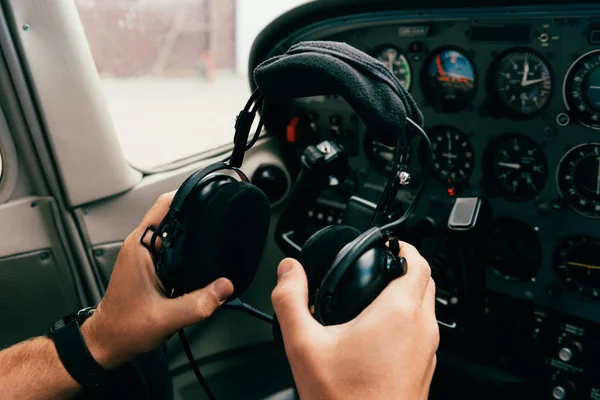 Vista parcial del piloto en el reloj de pulsera con auriculares en el avión - foto de stock