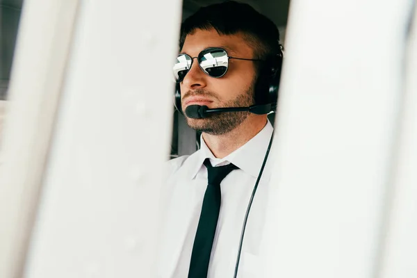 Pilote sérieux dans les lunettes de soleil et le casque regardant loin — Photo de stock