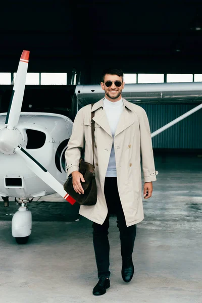 Piena vista lunghezza di elegante uomo d'affari in piedi cappotto vicino aereo — Foto stock