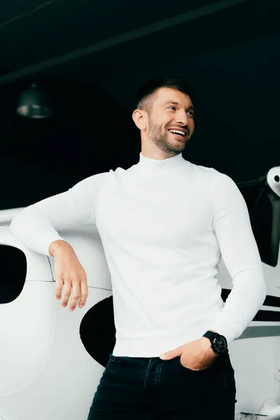 Handsome young man standing with hand in pocket near plane — Stock Photo