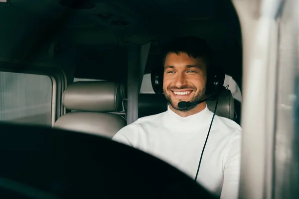 Sorrindo bonito barbudo piloto no fone de ouvido no avião — Fotografia de Stock