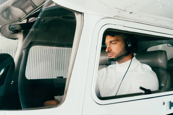 Сфокусированный бородатый пилот в гарнитуре сидит в самолете — стоковое фото