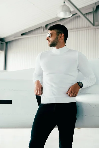 Pensive man in sunglasses standing near plane and looking away — Stock Photo