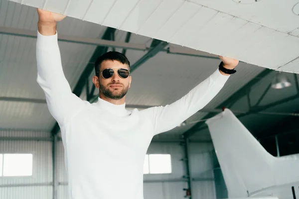 Cher homme barbu dans des lunettes de soleil debout près de l'avion — Photo de stock