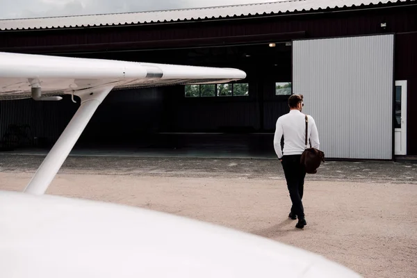 Visão traseira do homem com saco andando perto do avião — Fotografia de Stock