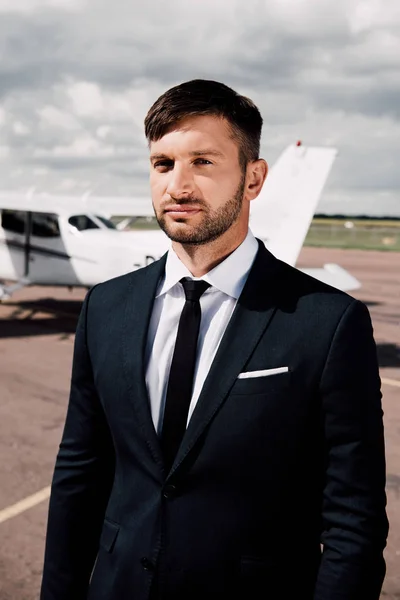 Confident bearded businessman in formal wear standing near plane — Stock Photo