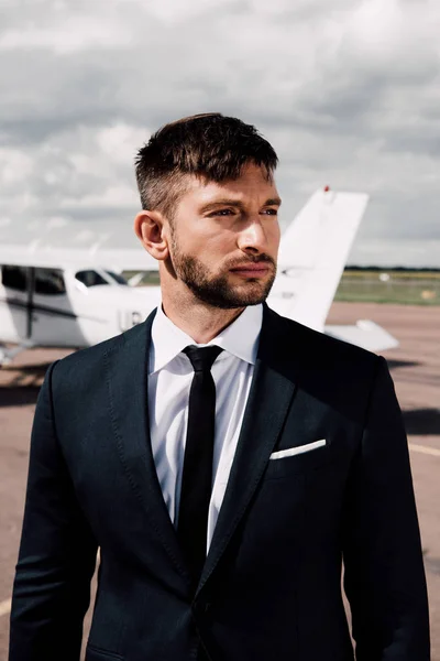 Confident bearded businessman in formal wear standing near plane — Stock Photo