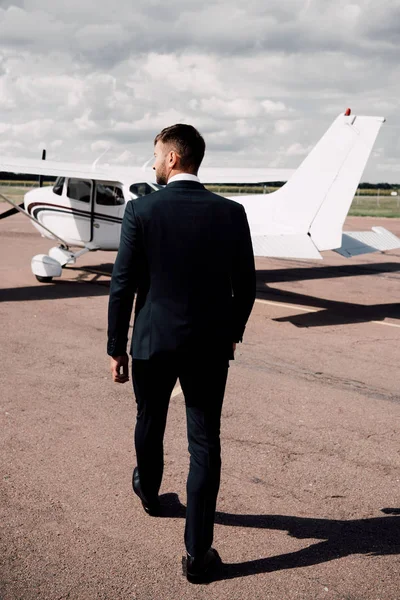 Vista posteriore di uomo d'affari in abbigliamento formale a piedi vicino aereo — Foto stock