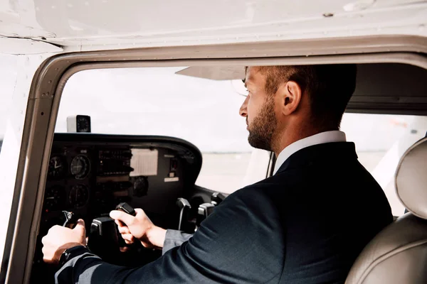 Piloto em desgaste formal sentado no avião e segurando — Fotografia de Stock
