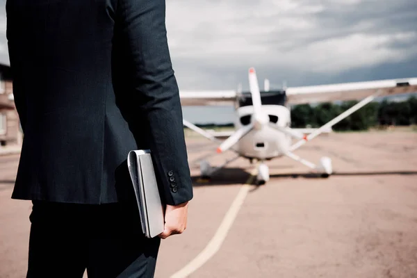 Partial view of businessman in formal wear holding laptop and map in sunny day — Stock Photo