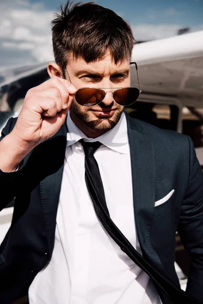 Selbstbewusster Geschäftsmann in offizieller Kleidung steht in der Nähe von Flugzeug — Stockfoto