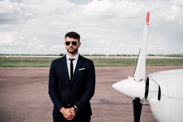 Uomo d'affari fiducioso in abbigliamento formale in piedi vicino aereo — Foto stock