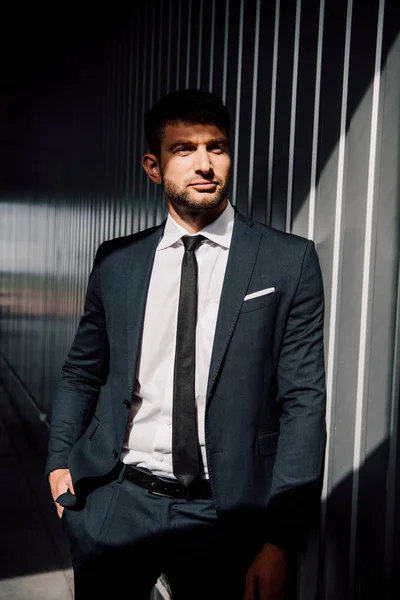 Уверенный в себе бизнесмен в формальной одежде стоя с рукой в кармане — стоковое фото