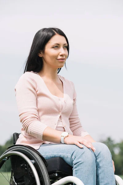 Mujer discapacitada feliz mirando hacia otro lado mientras descansa en el parque - foto de stock