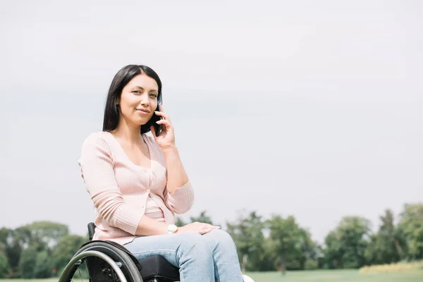 Счастливая женщина-инвалид разговаривает на смартфоне во время отдыха в парке — стоковое фото