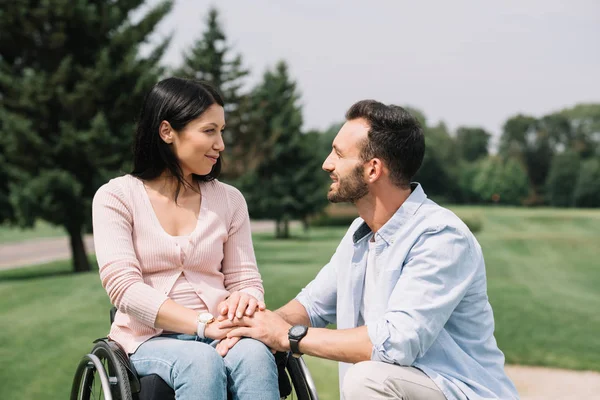 Happy handsome man looking at smiling disabled girlfriend in park — Stock Photo