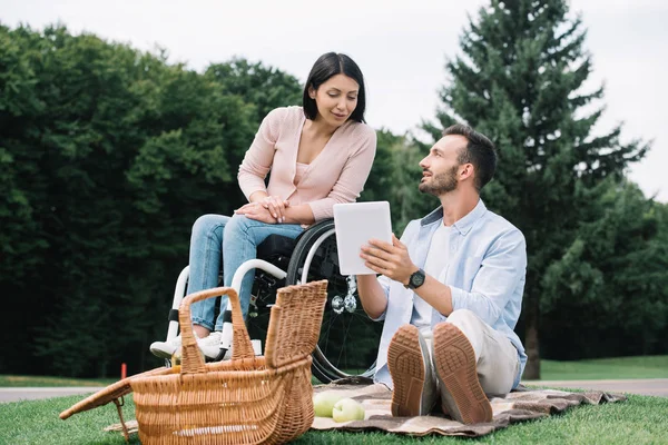 Allegra donna disabile e fidanzato sorridente utilizzando tablet digitale nel parco — Foto stock