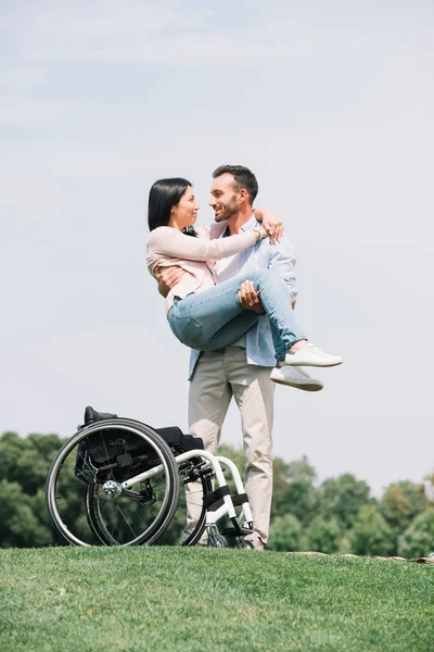 Happy young man holding on hands beautiful disabled girlfriend — Stock Photo