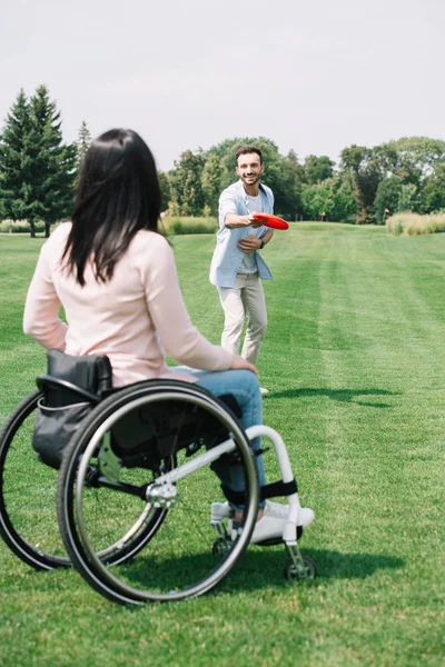 Vue arrière de la femme handicapée jouant avec disque volant avec petit ami gai dans le parc — Photo de stock