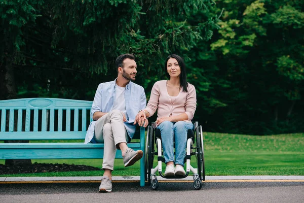 Schöner Mann mit glücklicher behinderter Frau beim gemeinsamen Ausruhen im Park — Stockfoto