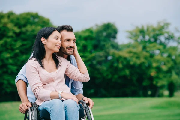 Happy disabled woman touching face of handsome boyfriend while resting in park together — Stock Photo