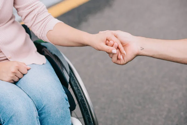 Vista parcial de la mujer discapacitada cogida de la mano con el novio - foto de stock