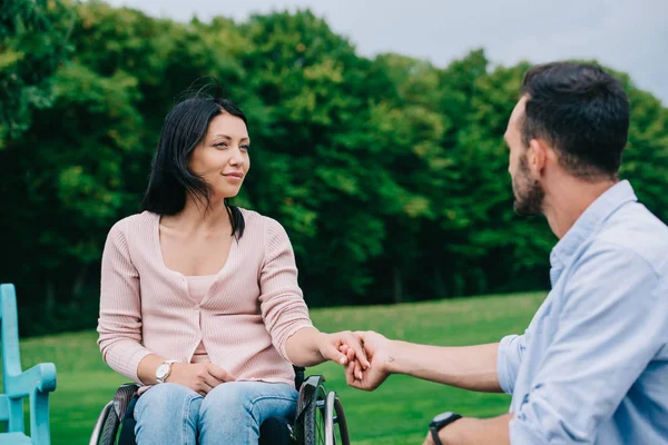 Felice donna disabile che si tiene per mano con il fidanzato mentre riposa nel parco insieme — Foto stock