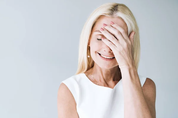 Mujer madura rubia feliz con los ojos cerrados aislados en gris - foto de stock