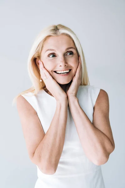 Sorridente donna matura bionda distogliendo lo sguardo isolato sul grigio — Foto stock